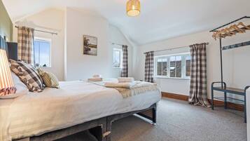 A bedroom with a bed, a window, a painting, and a hanging light fixture.