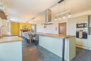 A modern kitchen with a central island, a dining area with chairs, and built-in appliances.