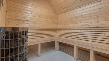 A sauna with wooden benches and a metal grid wall.