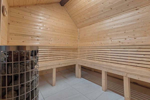 A sauna with wooden benches and a metal grid wall.