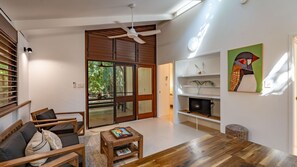 A modern living room with a wooden floor, a sofa, a coffee table, and a television.