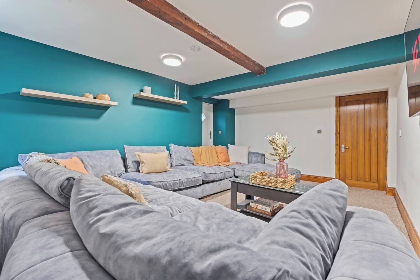 A modern living room with a sectional sofa, a coffee table, and teal walls.