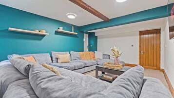 A modern living room with a sectional sofa, a coffee table, and teal walls.