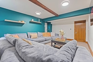 A modern living room with a sectional sofa, a coffee table, and teal walls.