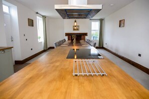 A conference room with a long table, chairs, a fireplace, and a view of the outdoors.