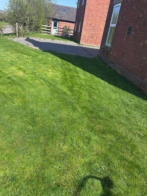 A well-maintained grassy area with a paved path leading to a brick building.