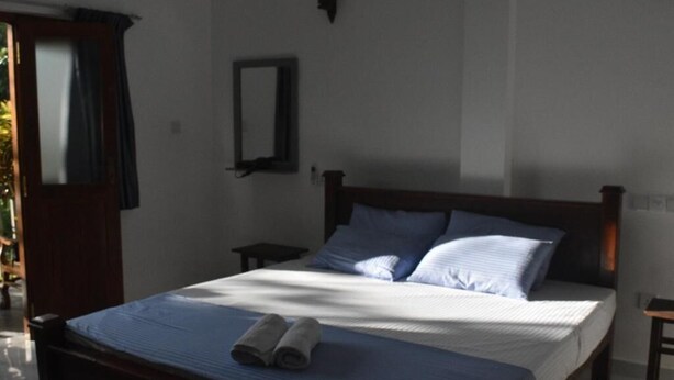 Ein Schlafzimmer mit Bett, Nachttisch, Spiegel und Tür.