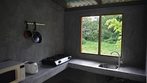 Eine kleine Küche mit Fenster, Mikrowelle, Toaster und Gasherd.