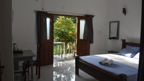 Ein Schlafzimmer mit Bett, Nachttisch, Spiegel und Blick auf einen Garten durch eine geöffnete Tür.