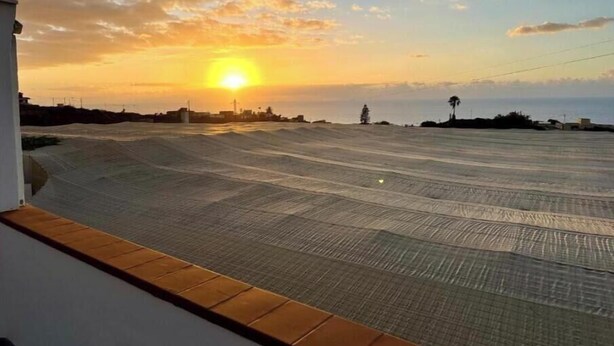 Tejado plano con vista al atardecer sobre un paisaje costero.