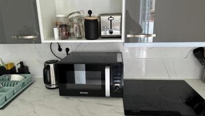 Una cocina con microondas, tostadora y cafetera sobre la encimera.