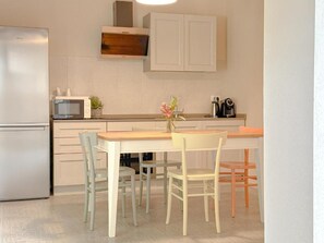 A kitchen with a refrigerator, microwave, cabinets, a coffee maker, and a table with chairs.