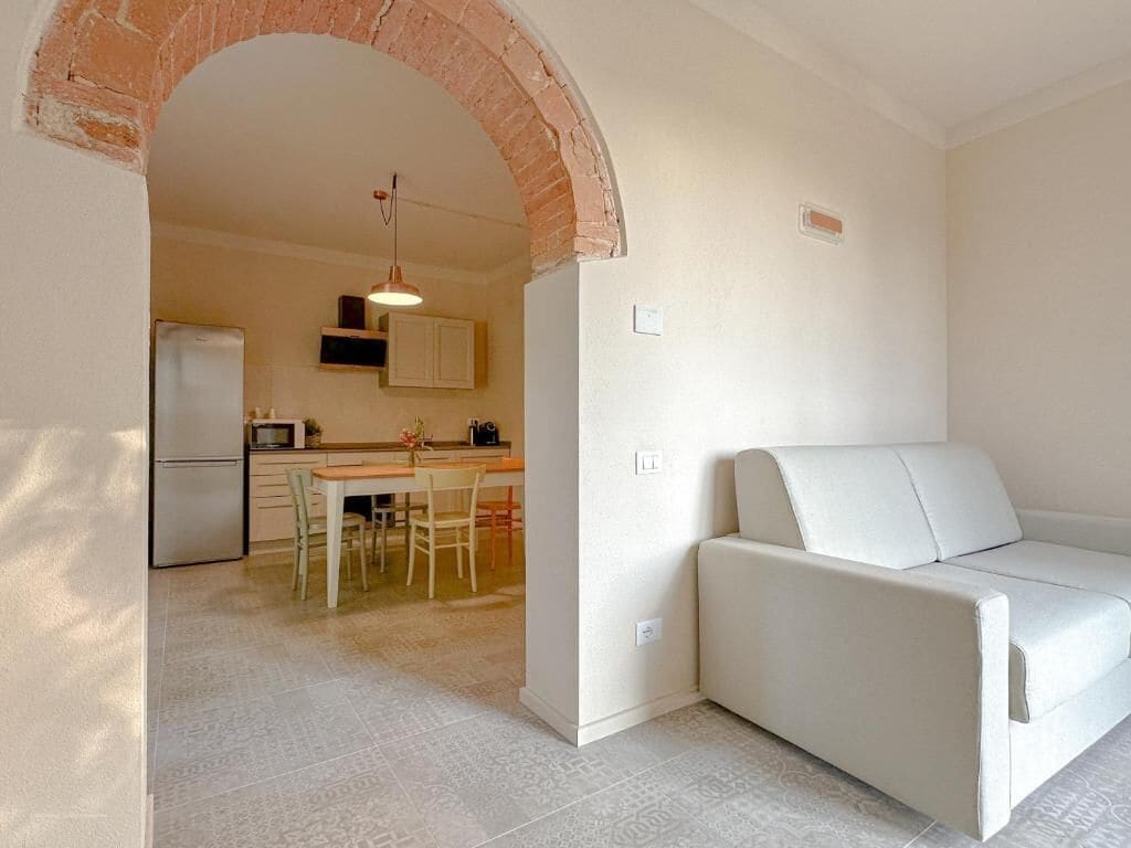 Una cocina moderna con zona de comedor, un sofá blanco y un arco de ladrillo.
