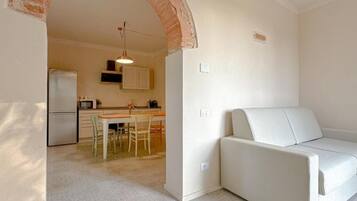 Una cocina moderna con zona de comedor, un sofá blanco y un arco de ladrillo.