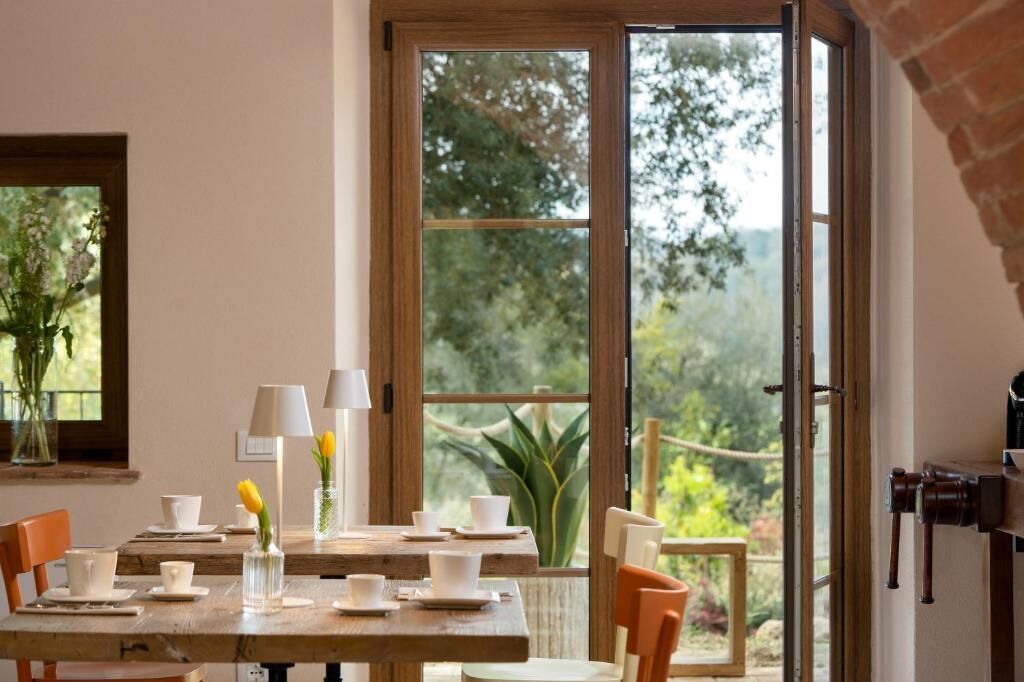 Un coin repas avec une table dressée pour quatre personnes, un vase rempli de fleurs et une vue sur la verdure à l’extérieur.