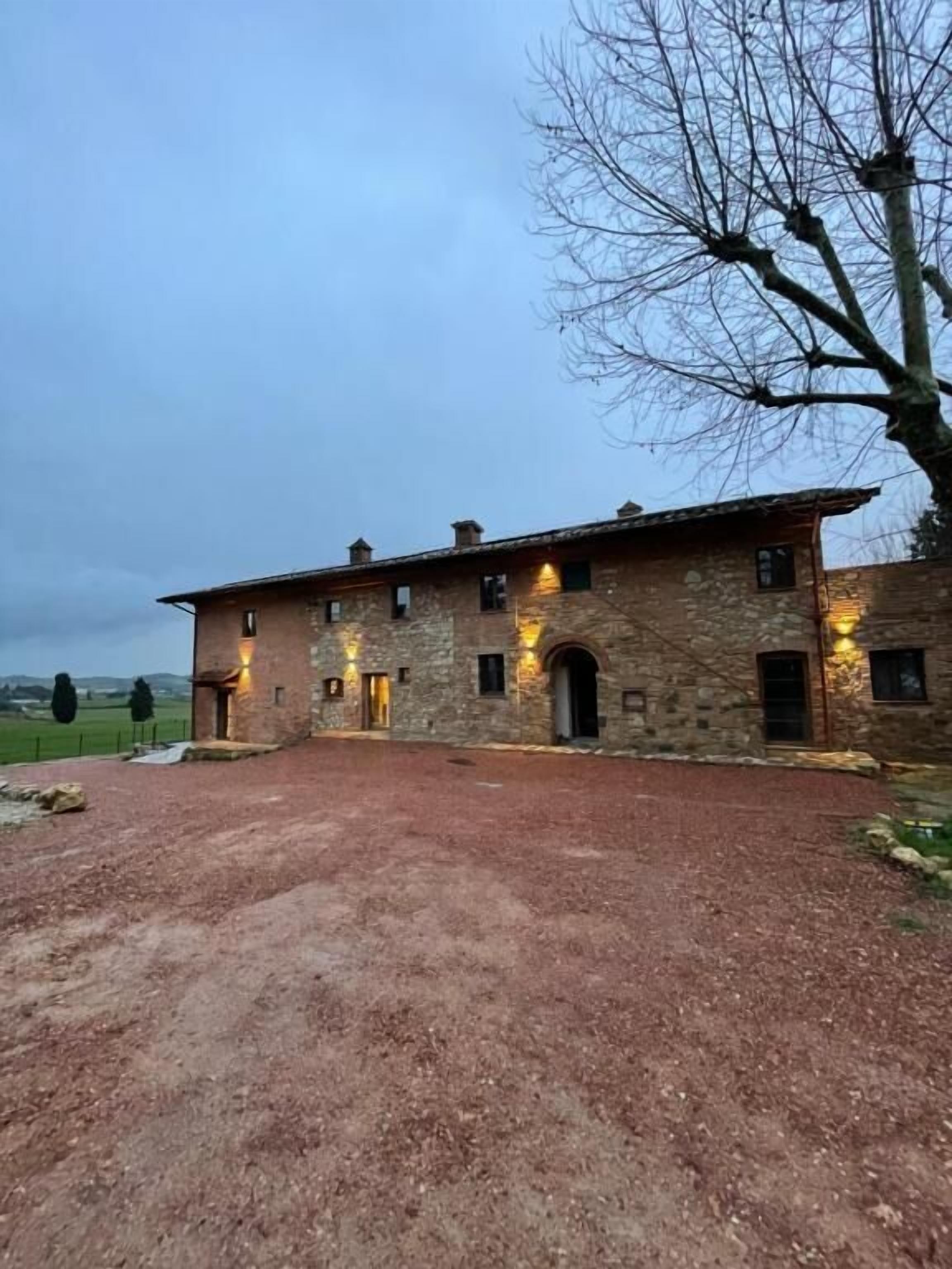 Un bâtiment en pierre doté de nombreuses fenêtres et une allée menant à l’entrée, recouverte de gravier.
