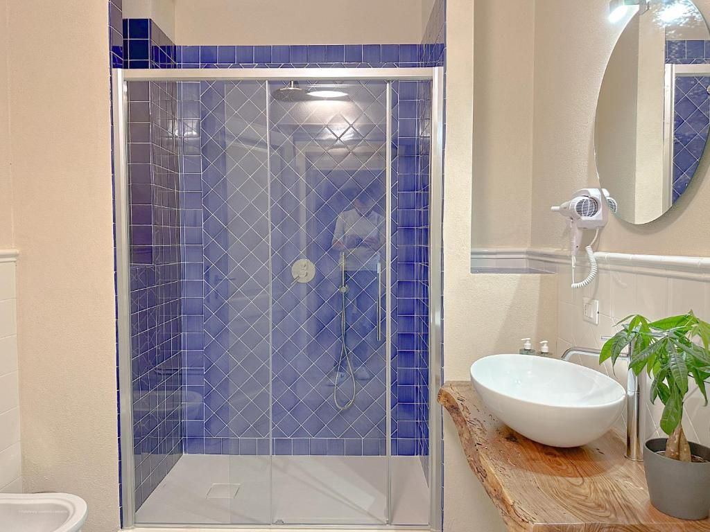 Un baño con ducha envuelta en vidrio, un lavamanos blanco y un espejo.