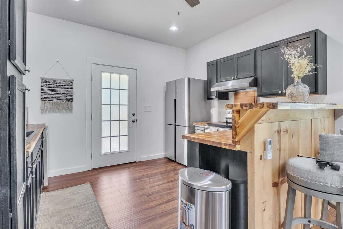 A modern kitchen with a wooden island, stainless steel appliances, and a view to the dining area.
