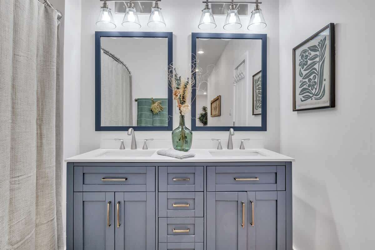 Un bagno con doppio lavabo, due lavandini e uno specchio sopra.