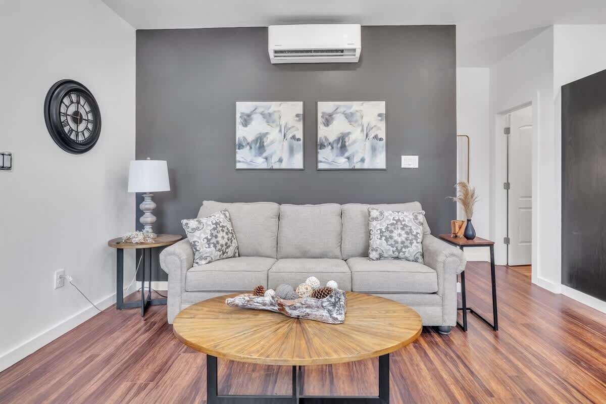 Ein Wohnzimmer mit grauem Sofa, rundem Couchtisch und zwei Wandklimaanlagen.