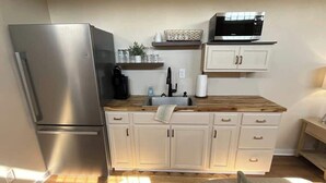 Una cucina compatta con frigorifero, forno a microonde e piano di lavoro in legno.