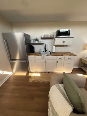 A compact kitchen with a refrigerator, microwave, and wooden countertop. - Suzy Two — Cozy Queen Suite Near MSU (Starkville)