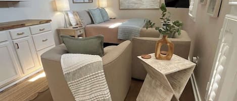 A modern living room with a sofa, a coffee table, and a TV mounted on the wall.