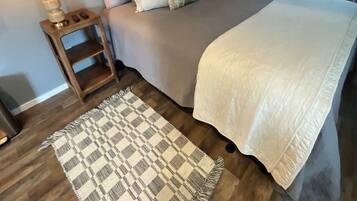Ein Schlafzimmer mit einem Bett, Nachttischlampen, einem gemusterten Teppich und Wanddekoration.