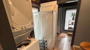 Cocina compacta con lavadora, refrigerador y piso de madera.