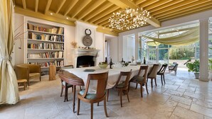 A dining area with a large table, chairs, and a fireplace.