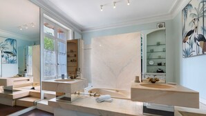 A modern bathroom with two sinks, a bathtub, and a large mirror.