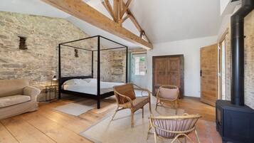 Une chambre dotée d’un lit à baldaquin, d’un plancher en bois, de murs en pierre et d’une cheminée.