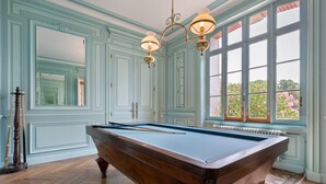 A pool table in a room with light blue walls and a large window.