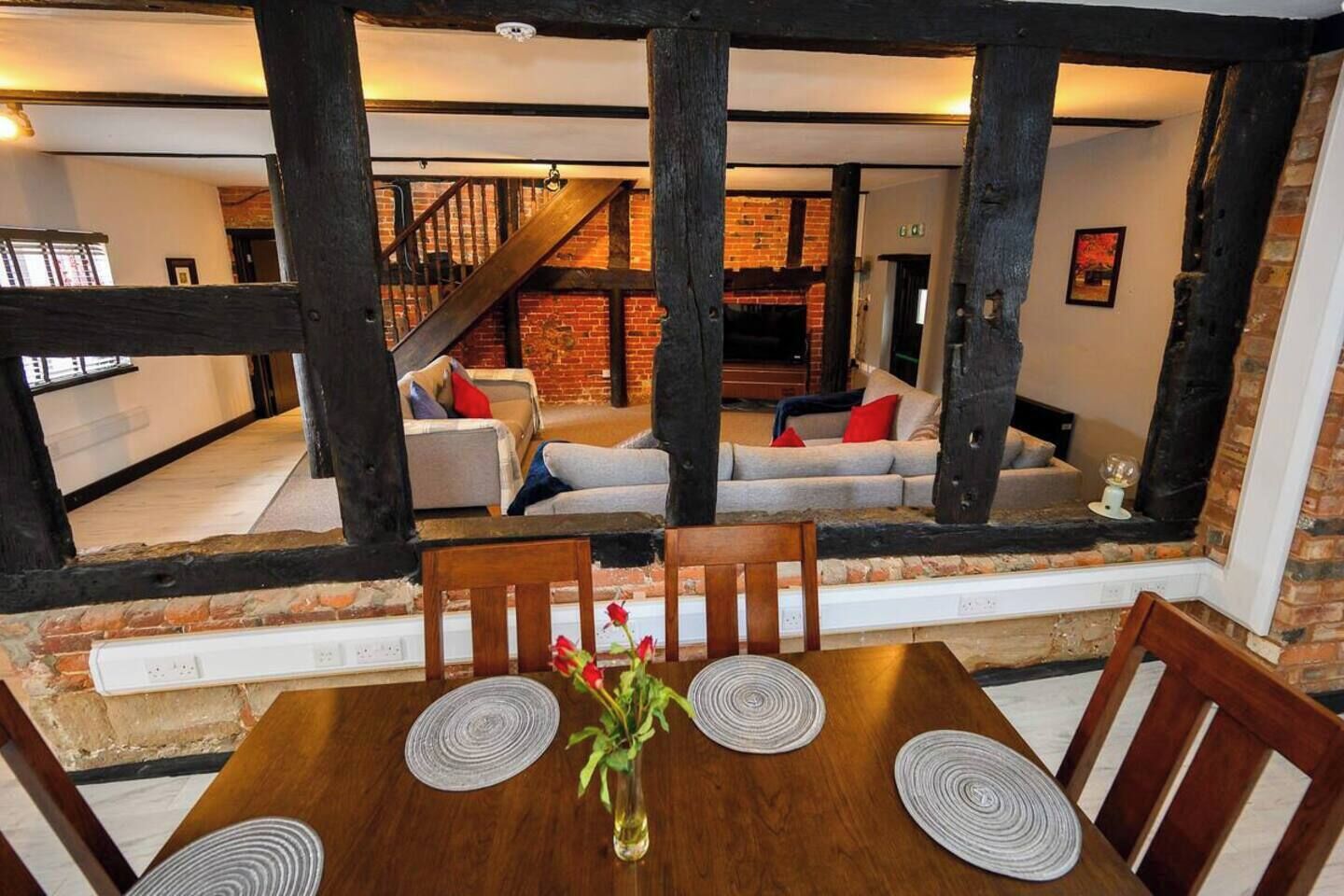 A dining area with a wooden table, chairs, and a vase with flowers.