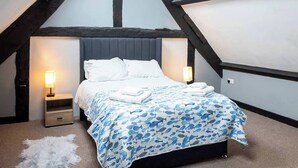 Quarto com cama, duas mesas de cabeceira, abajur fixado na parede e tapete de pele branca.