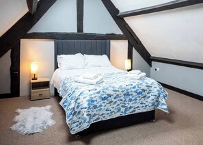 A bedroom with a bed, two bedside tables, a wall-mounted lamp, and a white fur rug.