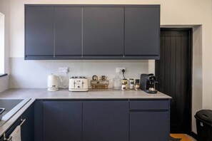 A compact kitchen with dark cabinets, a toaster, a coffee maker, and jars on the countertop.