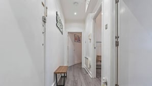 Un couloir avec un banc, une porte dotée d’une poignée et un luminaire fixé au mur.