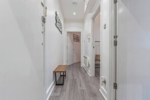 Un passadís amb una banca, una porta amb mànec i un llum penjant a la paret.