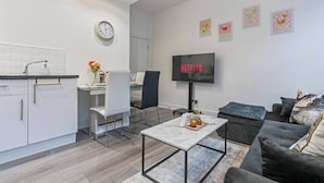 Un salon moderne comprenant un canapé, une table basse, un téléviseur à écran plat et un coin repas avec une table et des chaises.