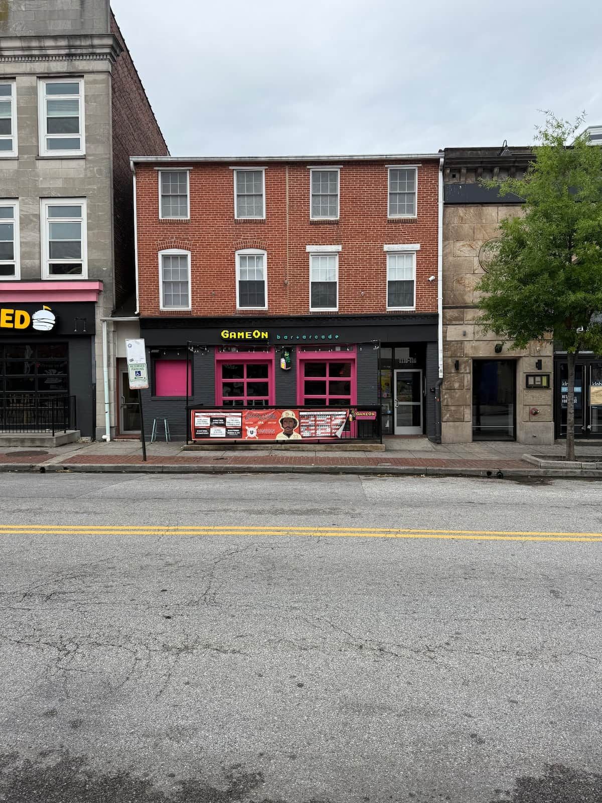 A street view with a building featuring a storefront with a sign that reads 'GAMEON bar arcade.'