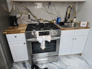 Eine Küche mit einem Gasherd, einem Backofen und einer Kaffeemaschine auf der Arbeitsfläche.