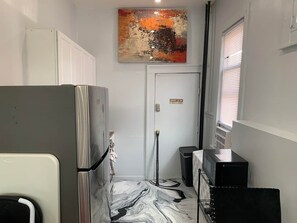 Eine kompakte Küche mit Kühlschrank, Mikrowelle und einer kleinen Arbeitsfläche.