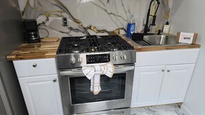 Eine Küche mit Edelstahlherd, Backofen und Marmorfliesenspiegel.