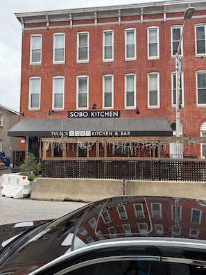 Um edifício de tijolos vermelhos com toldo preto identificado como 'SOBO KITCHEN & BAR'.