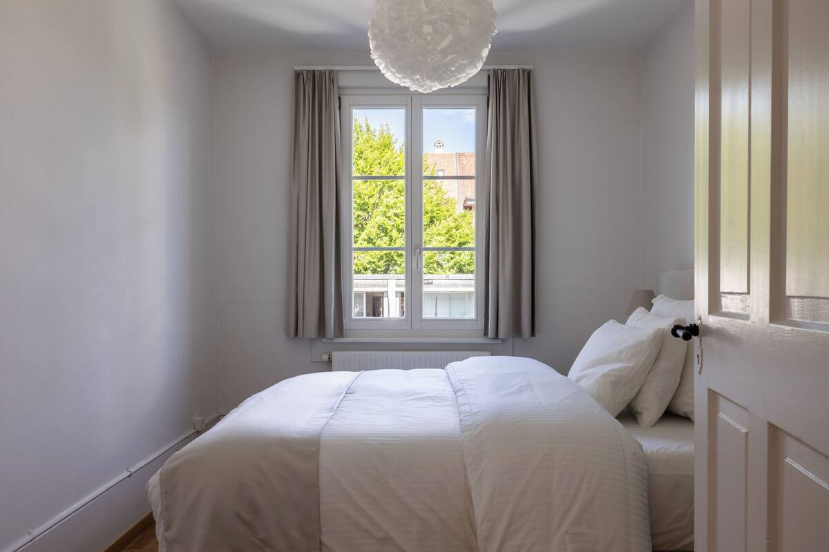 Un dormitorio con una cama grande, una ventana con cortinas y un radiador.