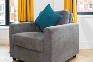 A grey armchair with a teal pillow in a room with yellow curtains and a window view. - #116 Modern 2 bed - 10 mins from Bullring & Grand Central (West Midlands)