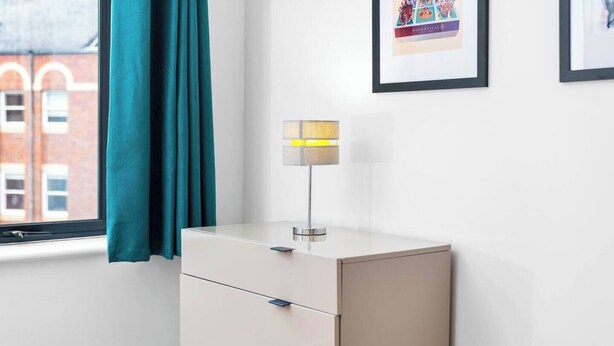 A minimalist room with a window, teal curtains, a white cabinet, and a framed picture on the wall. - #116 Modern 2 bed - 10 mins from Bullring & Grand Central (West Midlands)