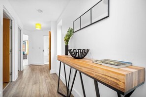 Ein Flur mit einem Holztischchen, einer Vase mit Blumen und einem gerahmten Bild an der Wand.