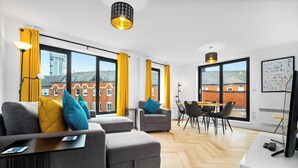 A modern living room with a sofa set, a dining area, and large windows with curtains. - #116 Modern 2 bed - 10 mins from Bullring & Grand Central (West Midlands)
